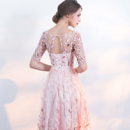 Frau in elegantem, rosa Abendkleid mit floralen Spitzenmustern und halblangen Ärmeln, Rückenausschnitt, stilvoller Look, festliche Mode.