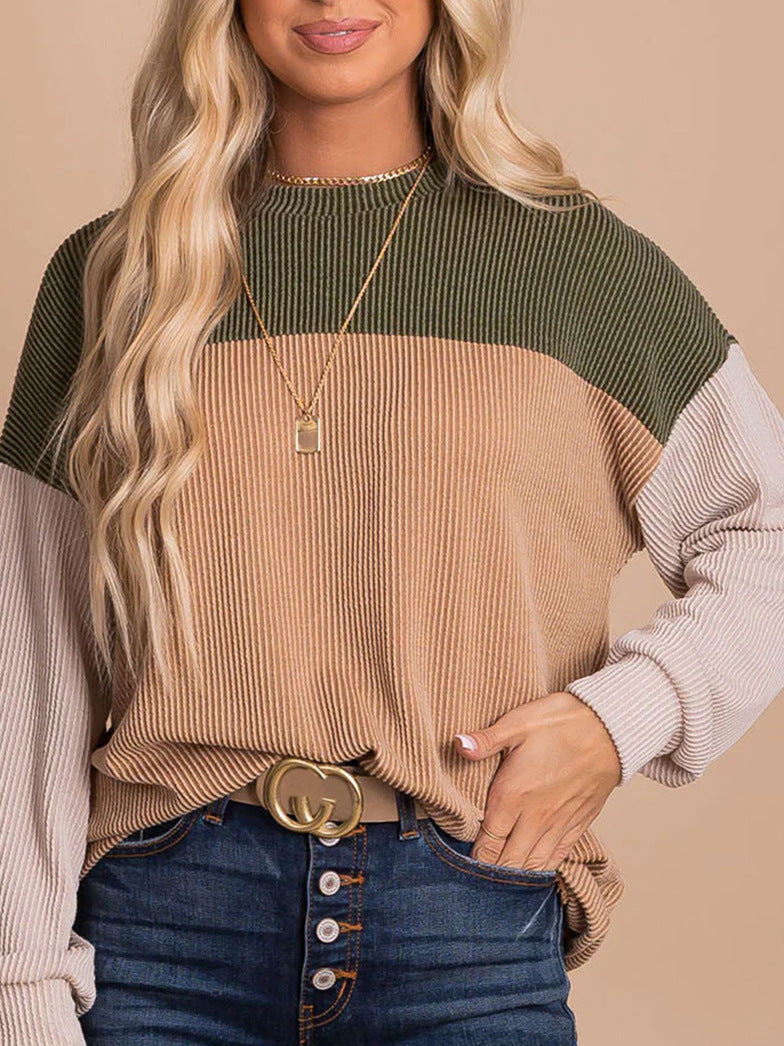 Frau mit welligem blondem Haar trägt gestreiften Pullover in Olivgrün, Beige und Creme, kombiniert mit blauer Jeans und goldener Halskette.