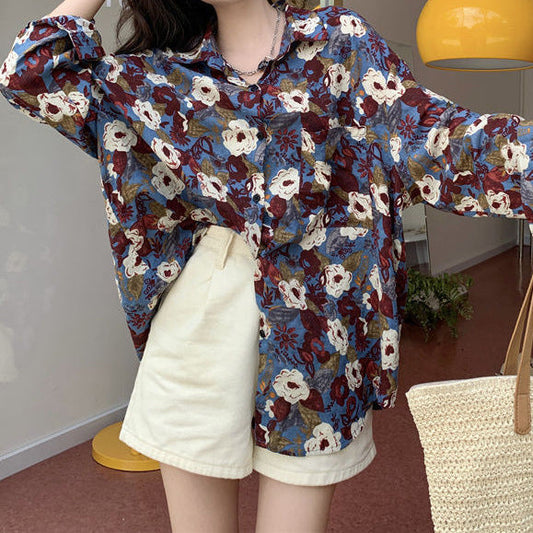 Frau trägt geblümte Bluse und weiße Shorts, hält Strohtasche. Modetrend, lässiger Sommerlook, florales Design, Damenmode.