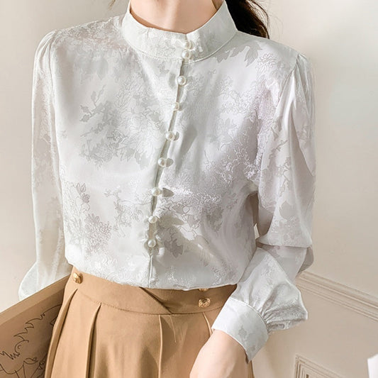 Weiße, elegante Bluse mit Stehkragen und Perlenknöpfen, kombiniert mit einem beigen Rock. Ideal für Büro- oder formelle Anlässe.