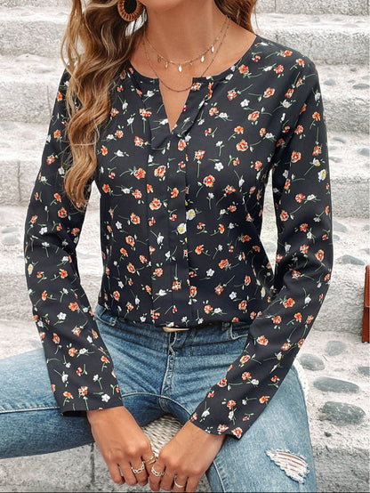 Frau in geblümter Bluse und Jeans sitzt auf Steintreppe. Modetrend, Damenmode, Freizeitlook, florales Muster, Herbstoutfit.