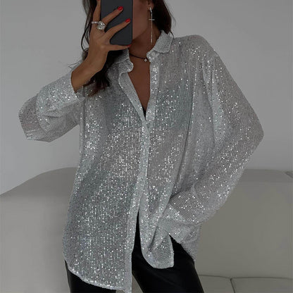 Frau in silberner Paillettenbluse, posiert auf weißem Sofa. Glitzerndes Hemd, modisches Outfit, eleganter Look, trendige Damenmode.