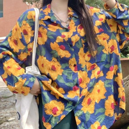 Frau trägt bunte Bluse mit gelbem Blumenmuster, hält weiße Stofftasche. Modetrend, florales Design, lässiger Stil, Herbstmode.
