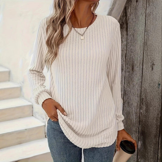 Frau in weißem gestreiftem Langarmshirt und blauer Jeans hält Kaffeebecher. Lässige Mode, Herbstoutfit, Damenbekleidung.