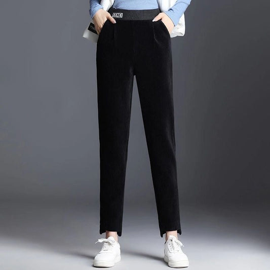 Schwarze Cordhose für Damen, kombiniert mit weißen Sneakers und blauem Pullover. Modische, bequeme Damenbekleidung für Herbst und Winter.