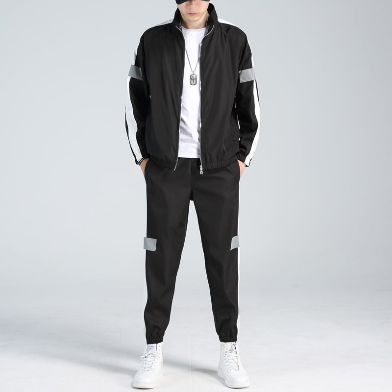 Schwarz-weißer Trainingsanzug für Herren, modisch, mit reflektierenden Streifen, kombiniert mit weißen Sneakers und T-Shirt, sportlicher Look.