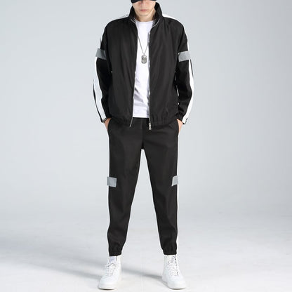 Schwarz-weißer Trainingsanzug für Herren, modisch, mit reflektierenden Streifen, kombiniert mit weißen Sneakers und T-Shirt, sportlicher Look.