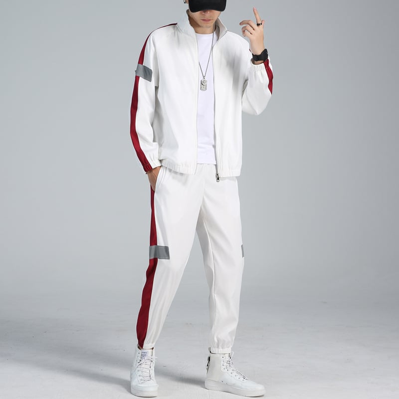 Mann in weißem Trainingsanzug mit roten Streifen, Baseballkappe und weißen Sneakers. Sportliche Mode, Freizeitkleidung, urbaner Stil.