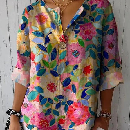 Bunte Damenbluse mit floralen Mustern, leuchtenden Blumen und Blättern auf hellem Hintergrund, ideal für Frühling und Sommermode.
