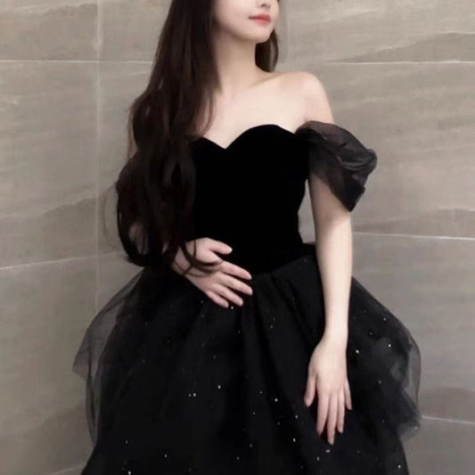 Frau in elegantem, schwarzem Abendkleid mit schulterfreiem Design und Tüllrock. Perfekt für formelle Anlässe und Abendveranstaltungen.