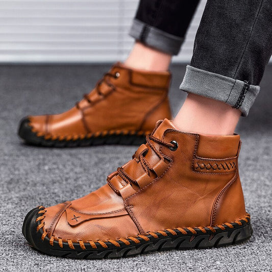 Braune Herren-Lederstiefel mit schwarzer Sohle, handgenäht, lässiger Stil, getragen mit hochgekrempelten Jeans. Ideal für Herbstmode.