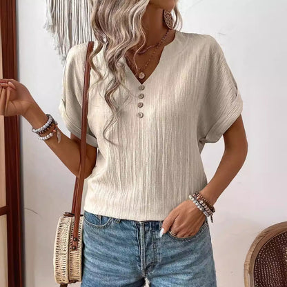 Frau in beiger Bluse mit Knopfleiste, blauen Jeans und Strohtasche. Modetrend, lässiger Sommerlook, Damenmode, Accessoires, Boho-Stil.