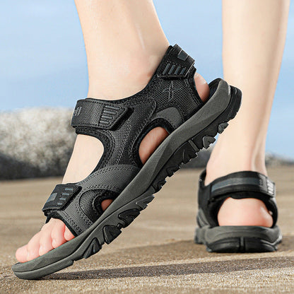 Schwarze Outdoor-Sandalen für Herren auf sandigem Untergrund, ideal für Wandern und Trekking. Robuste Sohle, verstellbare Riemen, atmungsaktives Material.