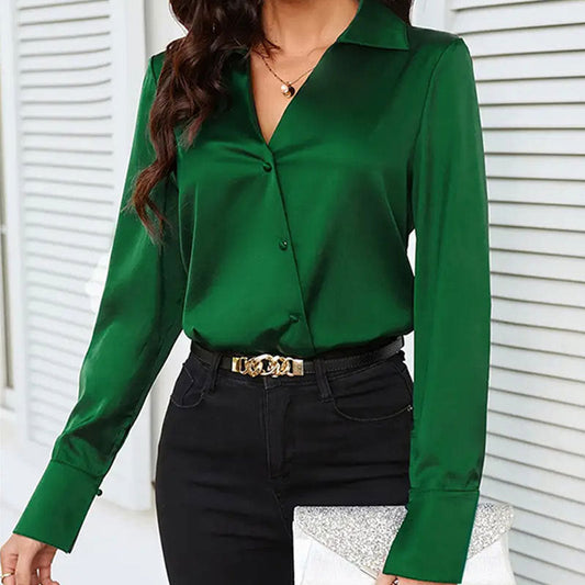 Frau in grüner Bluse und schwarzer Hose, hält silberne Clutch. Elegante Mode, stilvolle Damenbekleidung, modernes Outfit für Büro oder Abend.