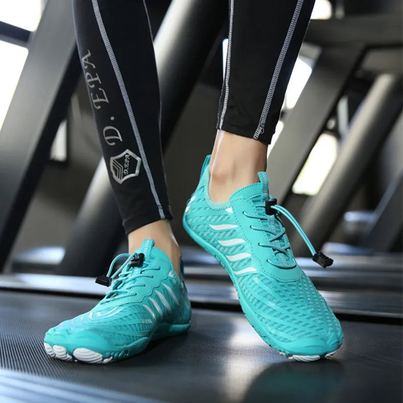 Türkise Barfußschuhe auf Laufband, getragen von Person in Sportleggings. Leichte, atmungsaktive Schuhe für Fitness und Outdoor-Aktivitäten.