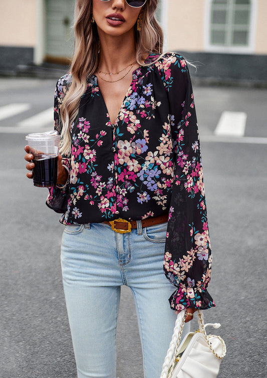 Frau in schwarzer, geblümter Bluse und blauer Jeans, hält ein Getränk und eine weiße Tasche. Modetrend, lässiger Streetstyle, Frühlingsmode.