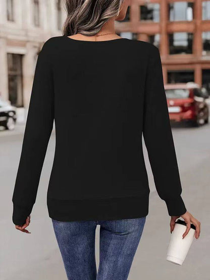 Frau in schwarzem Pullover und blauer Jeans hält Kaffeebecher, geht auf städtischer Straße. Mode, Freizeitkleidung, Stadtleben.