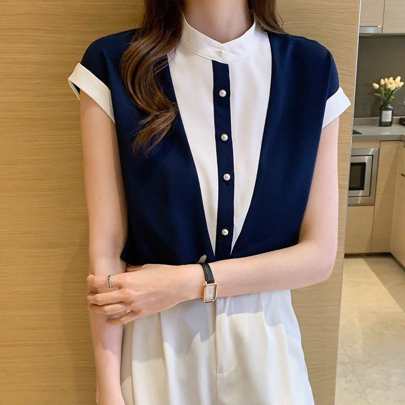 Frau in eleganter, zweifarbiger Bluse mit Knopfleiste, steht in moderner Küche. Stilvolle Mode, Damenbekleidung, zeitloses Design.