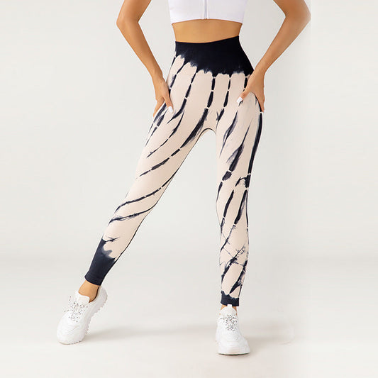 Frau in modischen, schwarz-weiß gestreiften Leggings und weißem Top, trägt weiße Sneakers. Sportliche Damenmode, Fitnessbekleidung, trendige Leggings.
