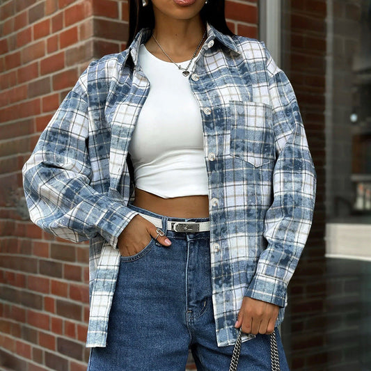Frau in kariertem Hemd und weißem Crop-Top, kombiniert mit blauen Jeans. Modetrend, lässiger Streetstyle, Herbstmode 2023.