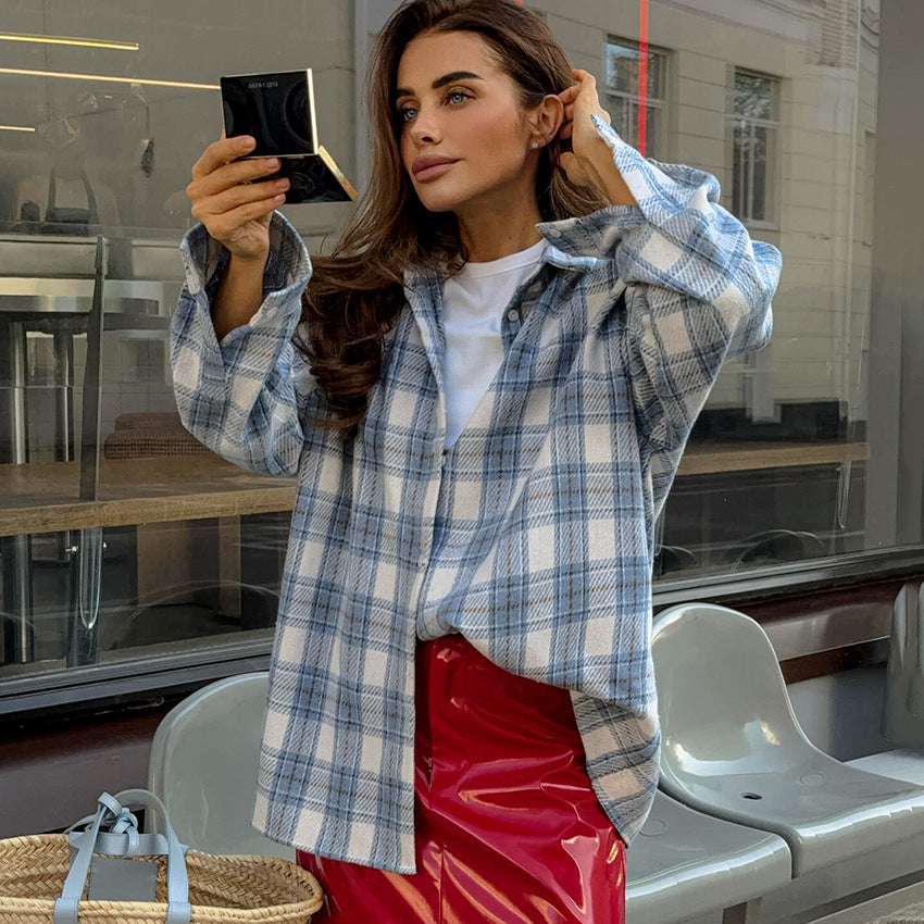 Frau in kariertem Hemd und rotem Rock betrachtet sich in einem Spiegel. Mode, Streetstyle, Herbstlook, urbane Kulisse, trendige Kleidung.