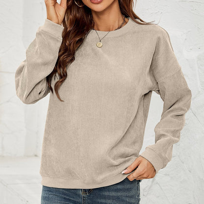Frau in beigem Cordpullover, lässig gestylt mit blauen Jeans. Modetrend Herbst, gemütlicher Look, Damenmode, Freizeitkleidung.