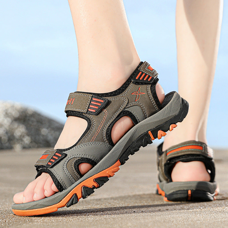 Outdoor-Sandalen für Herren mit rutschfester Sohle, ideal für Wandern und Trekking. Robustes Design in Grau und Orange auf steinigem Untergrund.