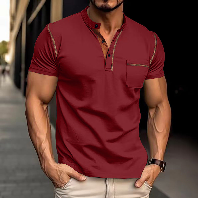 Mann in rotem Henley-Shirt mit kurzen Ärmeln und Knopfleiste, steht auf städtischem Gehweg. Modische Herrenbekleidung, urbaner Stil.