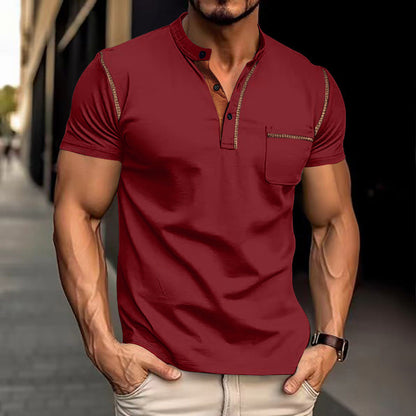 Mann in rotem Henley-Shirt mit kurzen Ärmeln und Knopfleiste, steht auf städtischem Gehweg. Modische Herrenbekleidung, urbaner Stil.