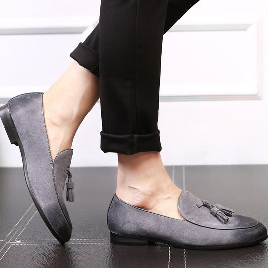 Graue Wildleder-Loafer mit Quasten, getragen von einer Person in schwarzer Hose. Elegante, bequeme Schuhe für Damenmode und Freizeitkleidung.