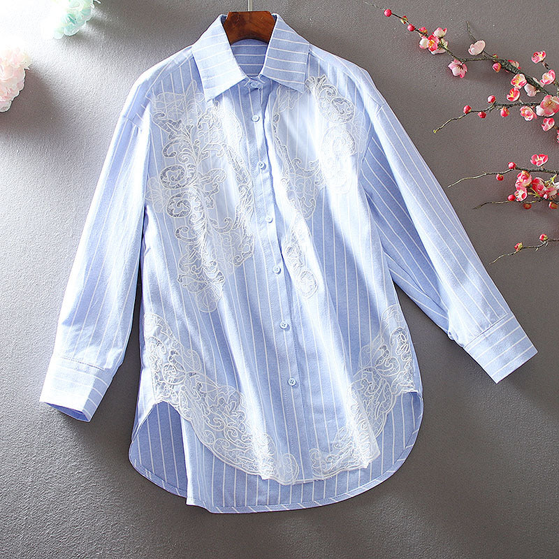 Hellblau gestreifte Damenbluse mit floraler Spitze, langärmlig, elegant, auf grauem Hintergrund mit Kirschblüten dekoriert. Ideal für Frühling.