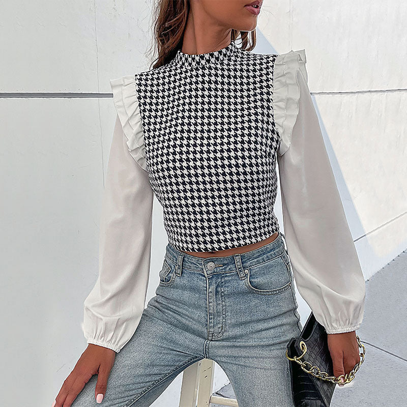 Frau trägt modisches Hahnentritt-Oberteil mit Rüschenärmeln und blauer Jeans. Stilvolle Damenmode, elegantes Design, trendiges Outfit.