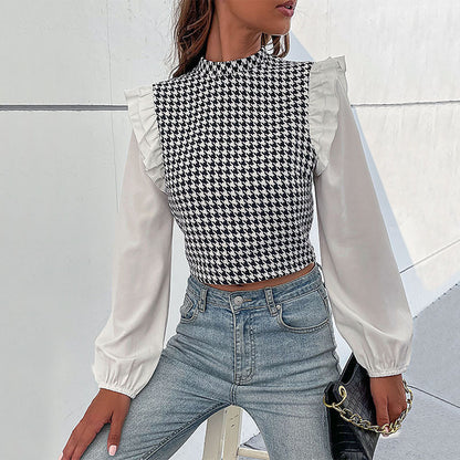 Frau trägt modisches Hahnentritt-Oberteil mit Rüschenärmeln und blauer Jeans. Stilvolle Damenmode, elegantes Design, trendiges Outfit.