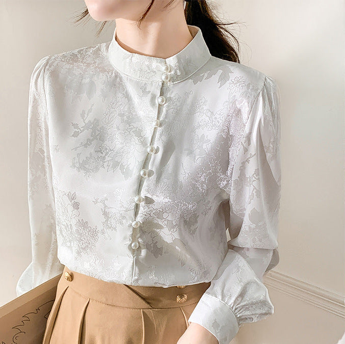 Frau in eleganter weißer Bluse mit Stehkragen und Knopfleiste, kombiniert mit braunem Rock. Stilvolle Damenmode, klassisch und zeitlos.
