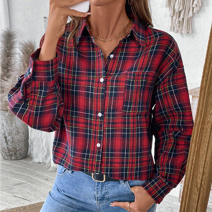Frau in rotem kariertem Hemd und blauer Jeans, hält Smartphone. Modetrend, lässiger Look, Herbstmode, Damenbekleidung, Innenaufnahme.
