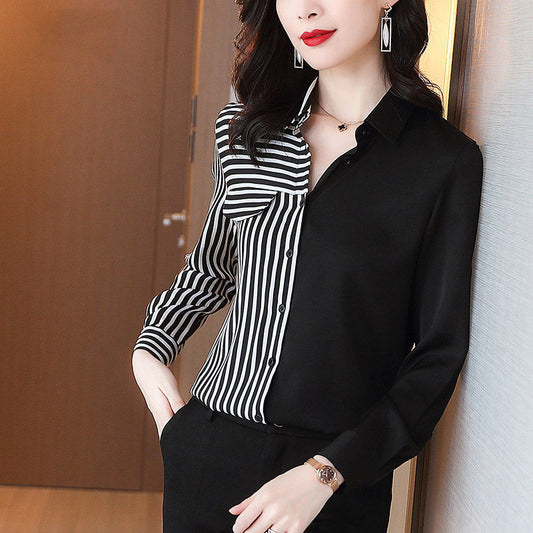 Elegante Frau in schwarz-weiß gestreifter Bluse, schwarze Hose, mit Schmuck, steht vor Holztür. Mode, Damenbekleidung, Business-Look.