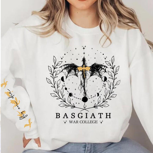 Frau trägt weißen Pullover mit Basgiath War College Design, schwarzem Drachenmotiv und astrologischen Symbolen. Trendige Fantasy-Mode.