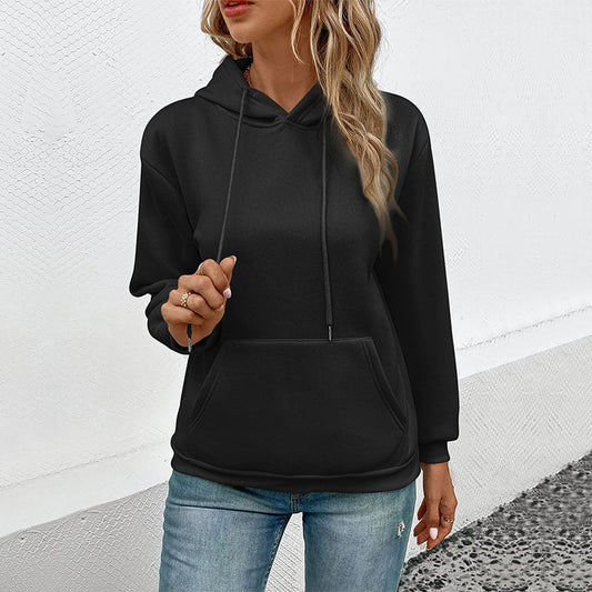 Frau in schwarzem Hoodie und blauer Jeans vor weißer Wand. Modetrend, lässiger Stil, Damenbekleidung, Streetwear, Herbstmode.