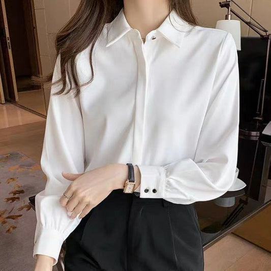 Frau in eleganter weißer Bluse und schwarzer Hose, trägt Armbanduhr. Businessmode, stilvolle Büro-Outfits, klassische Damenbekleidung.