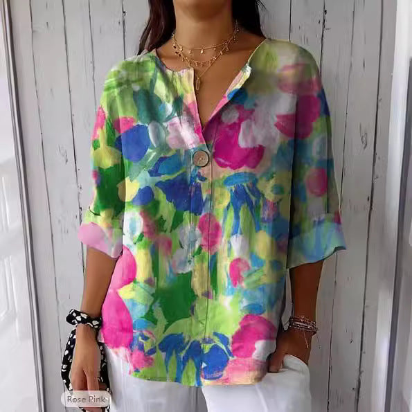 Frau trägt bunte, florale Bluse mit Knopfdetail vor Holzwand. Modetrend, Damenmode, Sommeroutfit, lässiger Stil, farbenfrohe Kleidung.