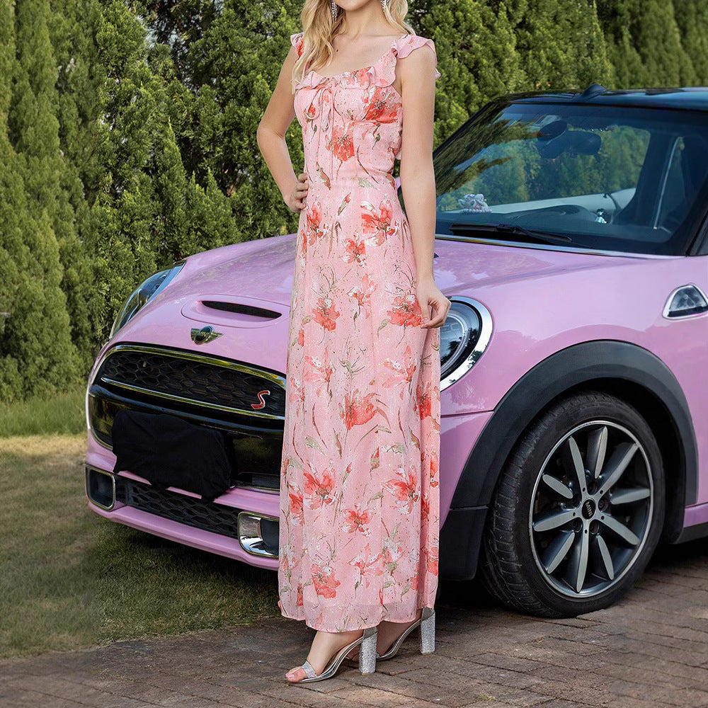 Frau in rosa Blumenkleid steht neben rosa Mini Cooper S, im Freien vor grünen Bäumen. Elegantes Sommeroutfit, stilvolles Auto.