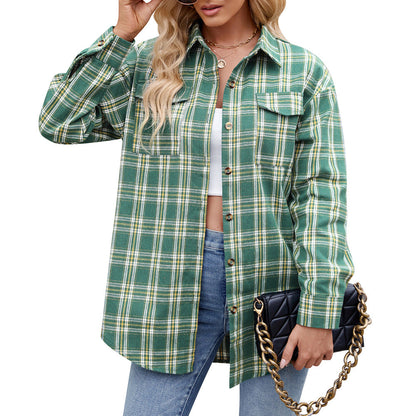 Frau in grüner karierten Hemdjacke, weißem Top und blauer Jeans, hält schwarze gesteppte Handtasche mit goldener Kette. Trendige Herbstmode.
