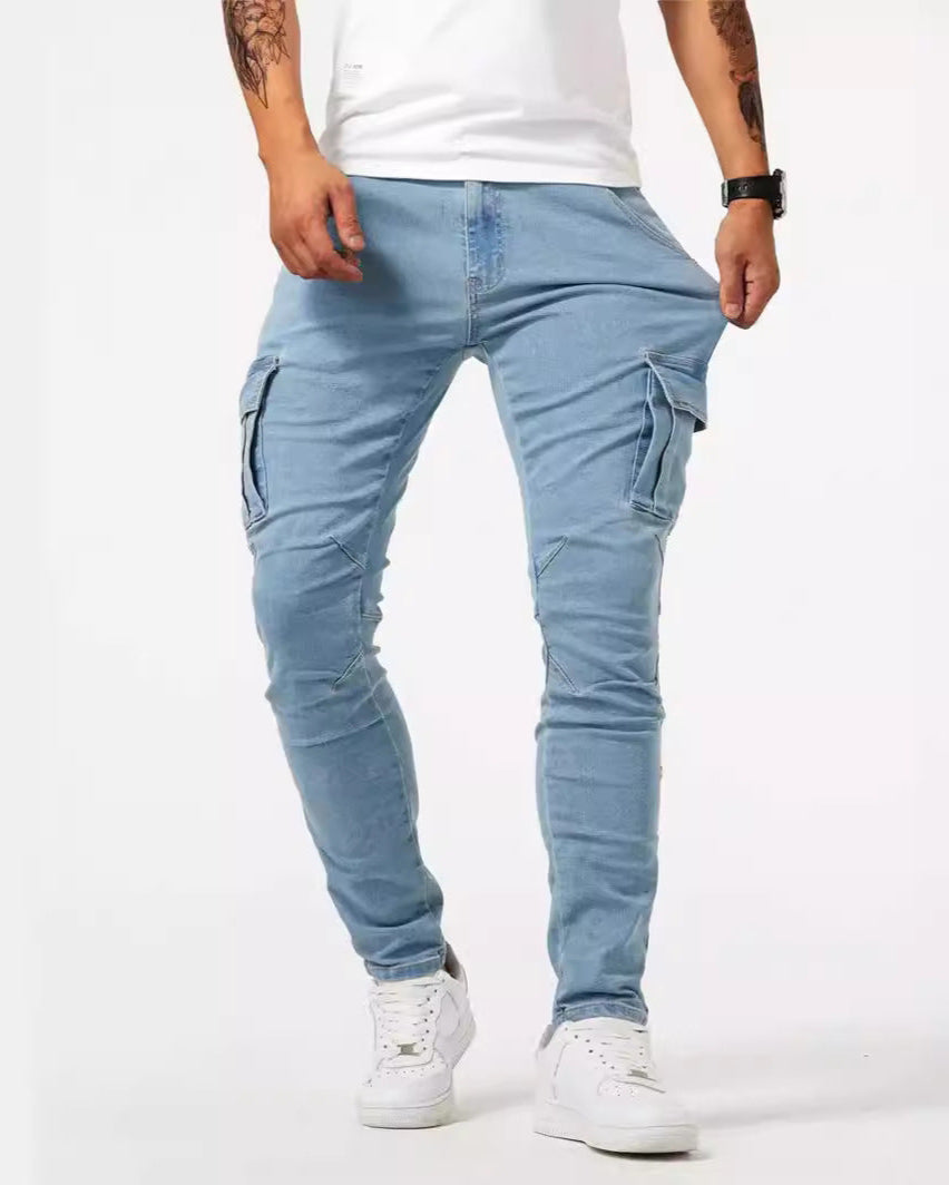 Mann in hellblauer Cargo-Jeans und weißem T-Shirt, trägt weiße Sneaker. Modische Herrenbekleidung, lässiger Stil, Streetwear-Trend.