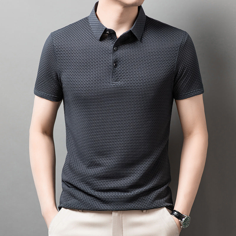 Mann trägt dunkelgraues Polohemd mit Strukturmuster, kurze Ärmel, Knopfleiste, kombiniert mit beigen Hosen. Elegante Herrenmode, Freizeitlook.