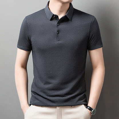 Mann trägt dunkelgraues Polohemd mit Strukturmuster, kurze Ärmel, Knopfleiste, kombiniert mit beigen Hosen. Elegante Herrenmode, Freizeitlook.