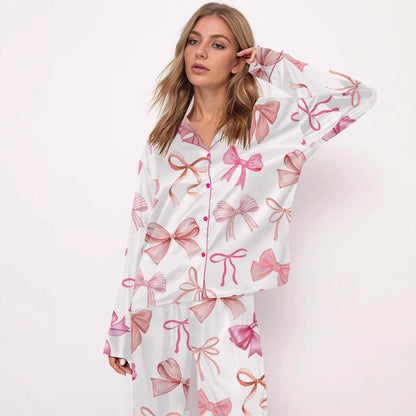 Frau in weißem Pyjama mit rosa Schleifenmuster, modisches Nachtwäsche-Design, entspannter Look, stilvolle Damenbekleidung, komfortable Schlafmode.