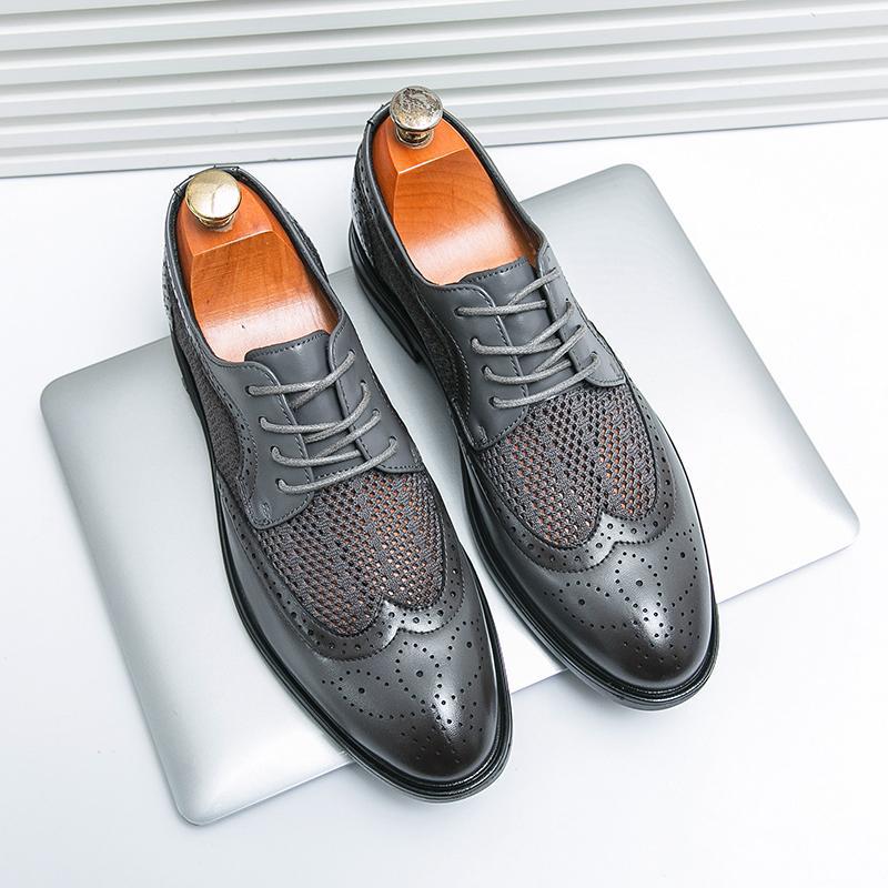 Elegante schwarze Brogues aus Leder mit Lochmuster auf silbernem Laptop. Herrenmode, Business-Schuhe, stilvolle Lederschuhe.