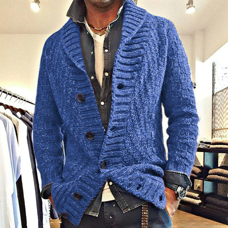 Mann trägt blauen Strick-Cardigan mit Schalkragen und großen Knöpfen, modisch kombiniert mit Hemd und Jeans, in einem Bekleidungsgeschäft.