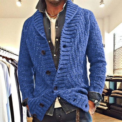 Mann trägt blauen Strick-Cardigan mit Schalkragen und großen Knöpfen, modisch kombiniert mit Hemd und Jeans, in einem Bekleidungsgeschäft.