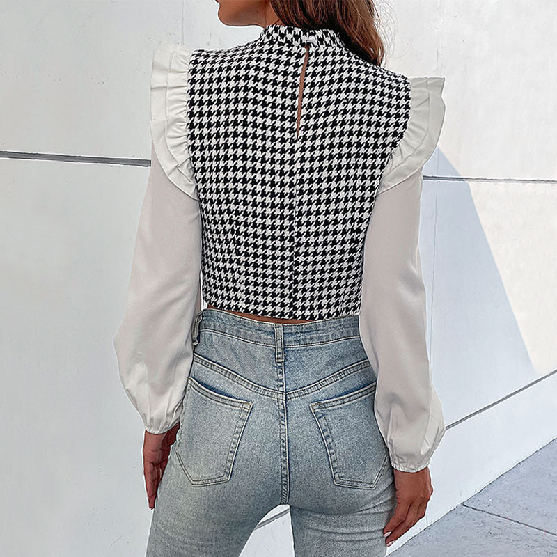 Frau in modischer Bluse mit Hahnentrittmuster und Rüschenärmeln, kombiniert mit hellblauen Jeans. Trendige Damenmode, stilvolles Outfit.